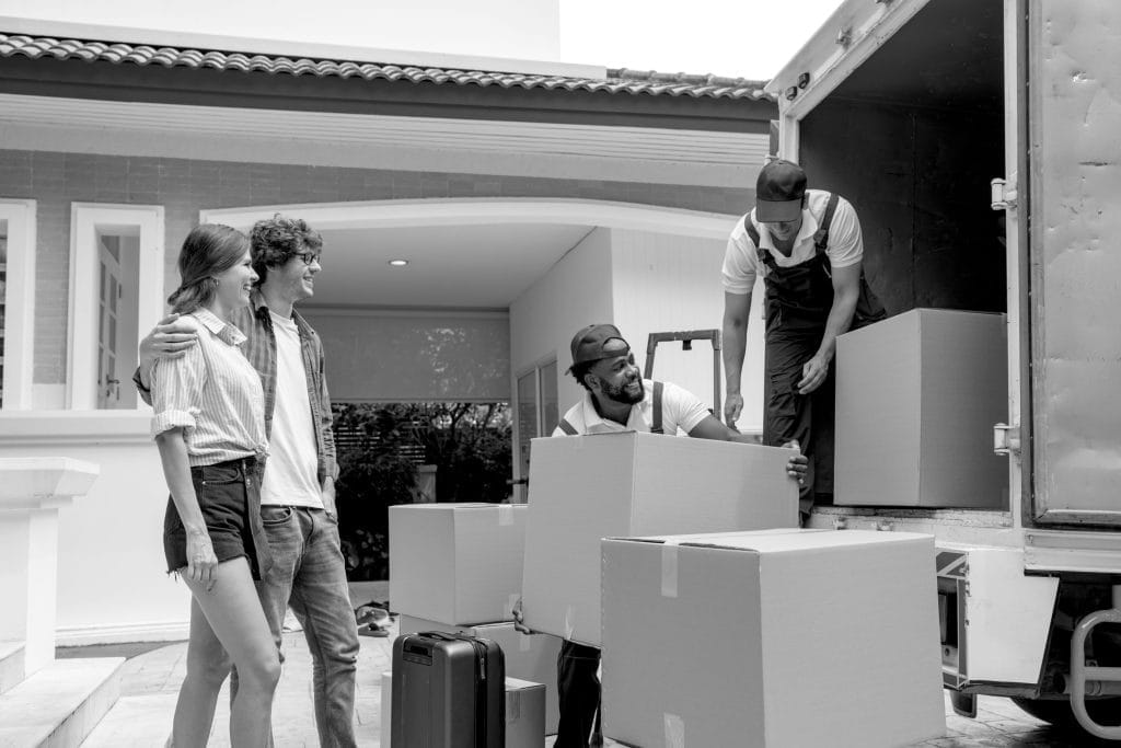 Couple overseeing movers unloading boxes from a truck in New York

